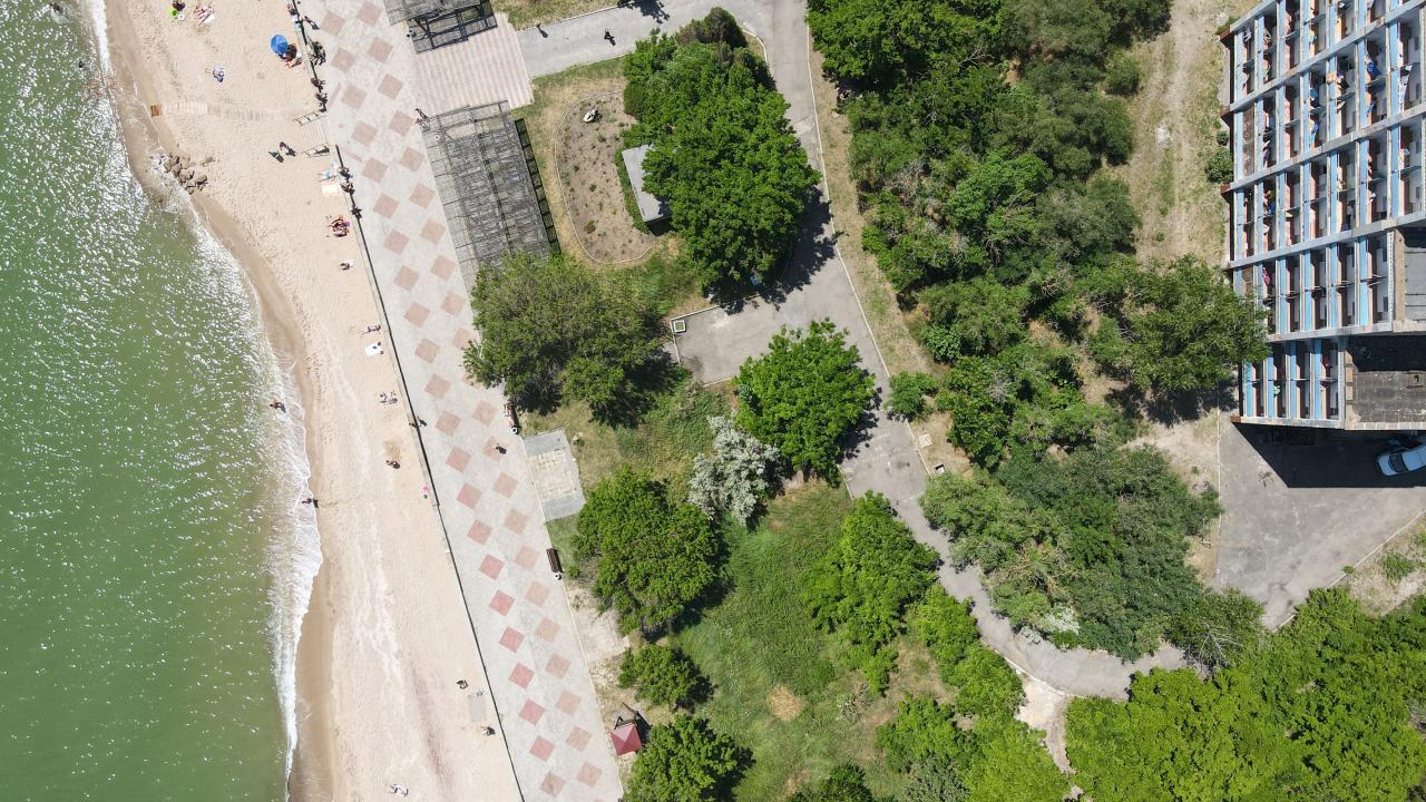 На фото вид сверху на главный корпус санатория зеленая зона и пляж